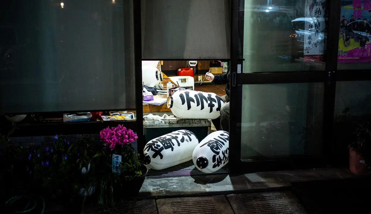 Seorang pria melukis lentera di daerah Asakusa di Tokyo (1/12). Suasana di Asakusa lebih tradisional daripada beberapa kawasan lain di Tokyo. (AFP Photo/Martin Bureau)
