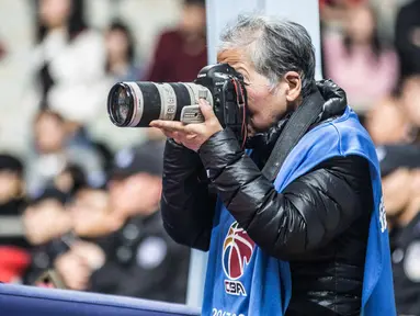Fotografer Hong Nanli mengambil gambar saat pertandingan bola basket di Shanghai (16/1). Hong Nanli 79 tahun memulai karirnya sebagai fotografer sejak 1979, ia juga merupakan fotografer olah raga tertua di China. (AFP Photo/China Out)