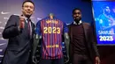 Bek Prancis, Samuel Umtiti dan Presiden Barcelona Josep Maria  berpose di samping jersey Barcelona pada pengumuman perpanjangan kontraknya di stadion Camp Nou, Senin (4/6). Umtiti memperpanjang kontraknya bersama Barcelona hingga 2022. (LLUIS GENE/AFP)