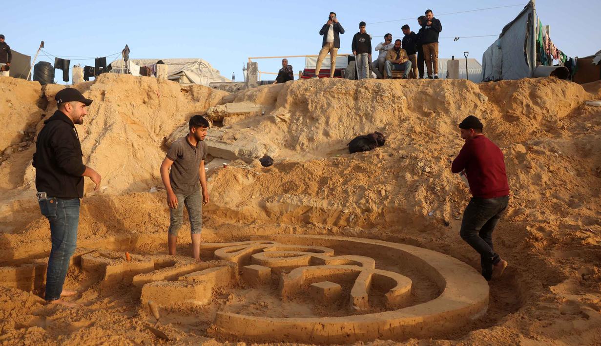 Selain ucapan Ramadan, Yazeed Abu Jarad sebelumnya juga dikenal karena membuat patung pasir angka "2026" di pantai Deir el-Balah pada akhir tahun 2025. Tampak dalam foto, warga membantu seniman Palestina, Yazeed Abu Jarad, saat ia membuat patung pasir dengan pesan ucapan "Selamat Datang, Ramadan" di sepanjang pantai di Khan Younis, selatan Gaza pada 17 Februari 2026. (Bashar Taleb/AFP)
