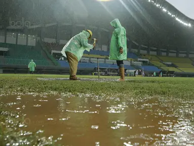 Petugas membuat lubang resapan untuk menguras air yang menggenangi lapangan di Stadion Patriot, Bekasi, Senin (13/11/2017). Drainase yang buruk menyebabkan lapangan terendam air. (Bola.com/M Iqbal Ichsan)