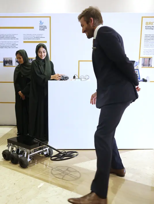 Mantan pemain sepak bola Inggris dan duta UNICEF, David Beckham bermain dengan robot yang dibuat oleh Tim Robotika Gadis Afghanistan di Forum Doha di ibukota Qatar