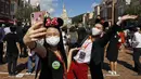 Para pengunjung yang mengenakan masker untuk mencegah penyebaran COVID-19 berswafoto di Disneyland Hong Kong, Kamis (18/6/2020). Disneyland Hong Kong kembali beroperasi pada 18 Juni 2020 dengan menerapkan sejumlah protokol kesehatan baru. (AP Photo/Kin Cheung)