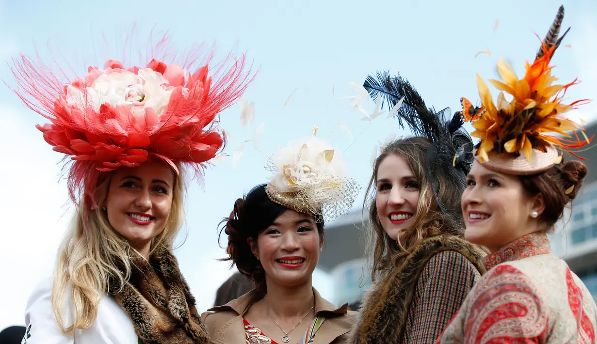 Wanita-wanita cantik mengunakan topi unik foto bersama sambut pembukaan ajang Pacuan Kuda dalam Festival Cheltenham di Inggris, (16/3). Pacuan kuda merupakan olahraga yang disukai oleh kerajaan Inggris. (REUTERS/Paul Childs)