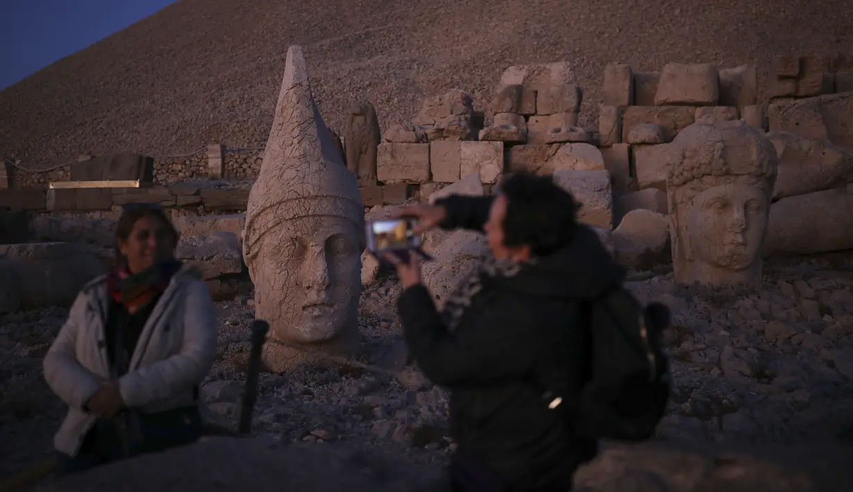 Gambar pada 23 September 2019 memperlihatkan wisatawan berfoto di Gunung Nemrut, Provinsi Adiyaman di Turki bagian tenggara. Pada puncak gunung yang berada di ketinggian 2.206 mdpl, terdapat puing reruntuhan Kerajaan Commagene. (AP/Emrah Gurel)