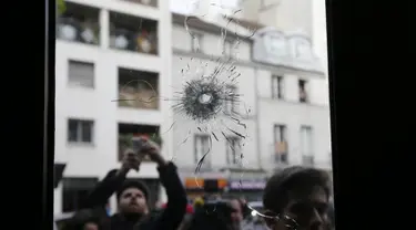 Wartawan tampak mengabadikan gambar kaca disebuah restoran dimana penembakan terjadi di Paris, Prancis, Sabtu (14/11/2015). Dikabarkan ratusan orang tewas dalam serangan ini. (REUTERS/Gonzalo Fuentes)