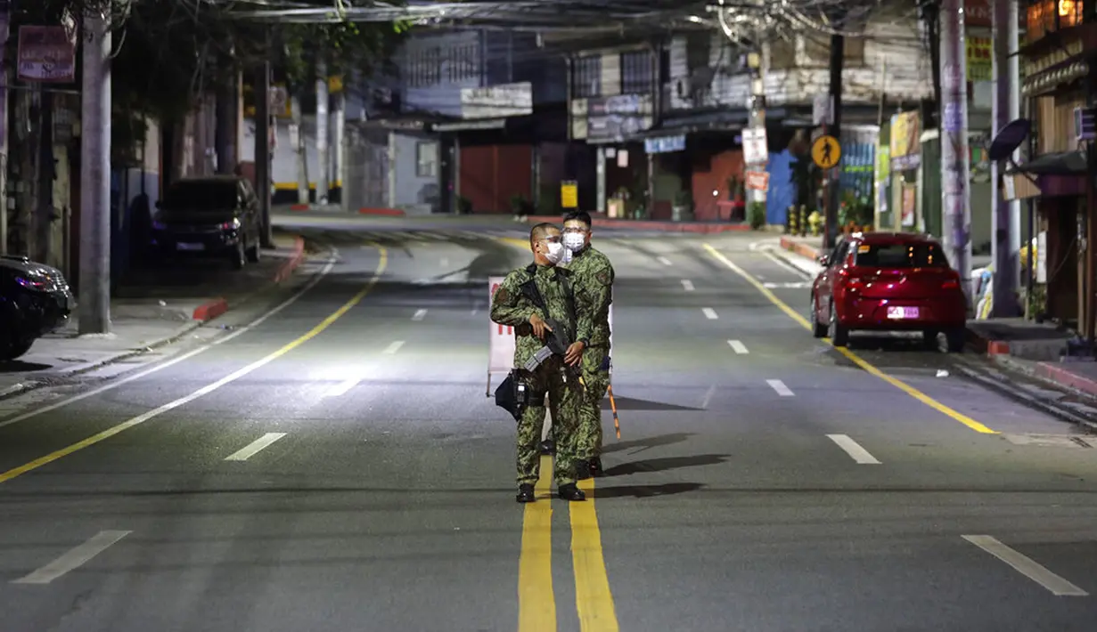 Polisi bersenjata berdiri di jalan kosong saat jam malam diberlakukan untuk mencegah penyebaran COVID-19 di Metro Manila, Filipina, Senin (15/3/2021). Lonjakan kasus COVID-19 di Filipina menambah kekhawatiran atas lambannya vaksinasi dan keengganan publik. (AP Photo/Aaron Favila)