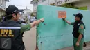 Petugas memasang plang di depan PT DKB Dok Perkapalan Galangan I, Tanjung Priok, Jakarta, Senin (23/11). Langkah ini diambil sebagai peringatan bagi para wajib pajak (WP) kelas menengah ke atas mencapai ratusan miliar. (Liputan6.com/Faizal Fanani)