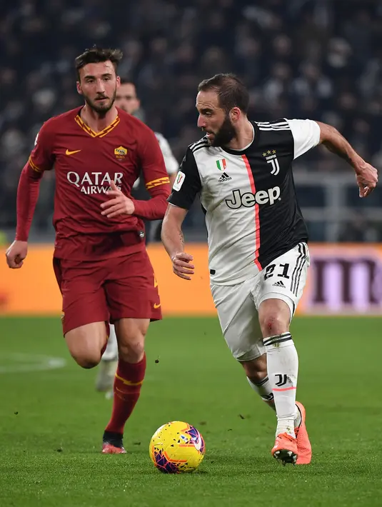 Pemain Juventus Gonzalo Higuain (kanan) menggiring bola melewati pemain AS Roma pada pertandingan Coppa Italia di Turin, Italia, Rabu (22/1/2020). Juventus menggilas AS Roma 3-1 dan berhasil lolos ke semifinal. (Marco Bertorello/AFP)