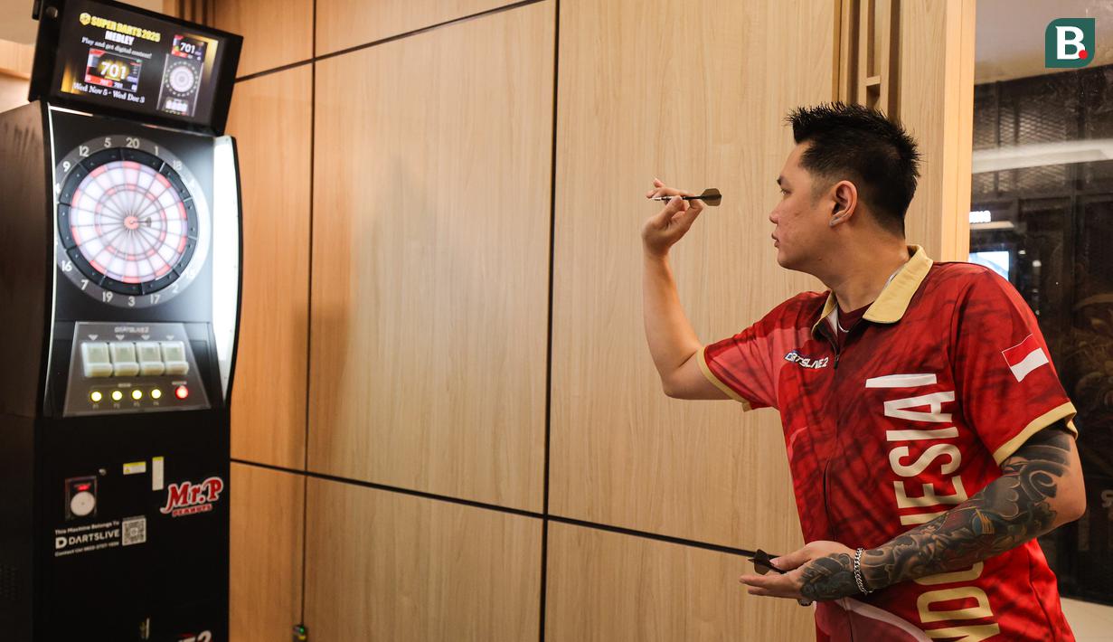 Pemain darts Indonesia Tirta Suparjo mencoba salah satu alat di acara peluncuran Darts Station di lantai F7 FX Sudirman, Senayan, Jakarta pada Sabtu (15/11/2025). (Bola.com/Abdul Aziz)