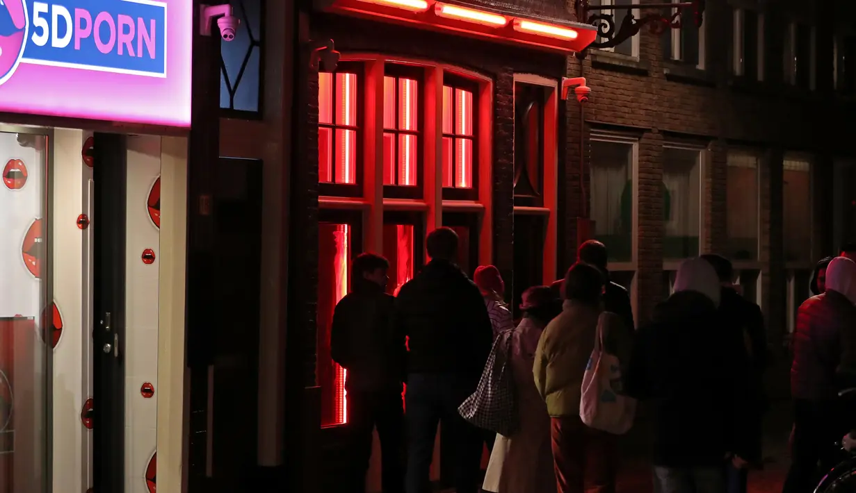 Orang-orang berjalan melewati rumah bordil di Red Light District Amsterdam, Belanda, Rabu (3/4). Pekerja seks komersial (PSK) di lokasi prostitusi tersebut mulai muak dengan turis karena dianggap sebagai atraksi wisata. (REUTERS/Yves Herman)