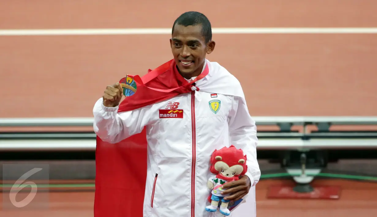 Pelari Indonesia, Agus Prayogo memamerkan medalinya di podium kemenangan di National Stadium, Singapura, Rabu (10/6/2015). Agus berhasil meraih emas di nomor lari 10.000 m putra SEA Games 2015. (Liputan6.com/Helmi Fithriansyah)