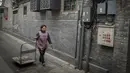 Seorang pekerja restoran menarik troli di sebuah jalan di daerah hutong di Beijing (26/2). Istilah "hutong", terdahulunya bermakna "perigi air". (AFP Photo/Nicolas Asfouri)