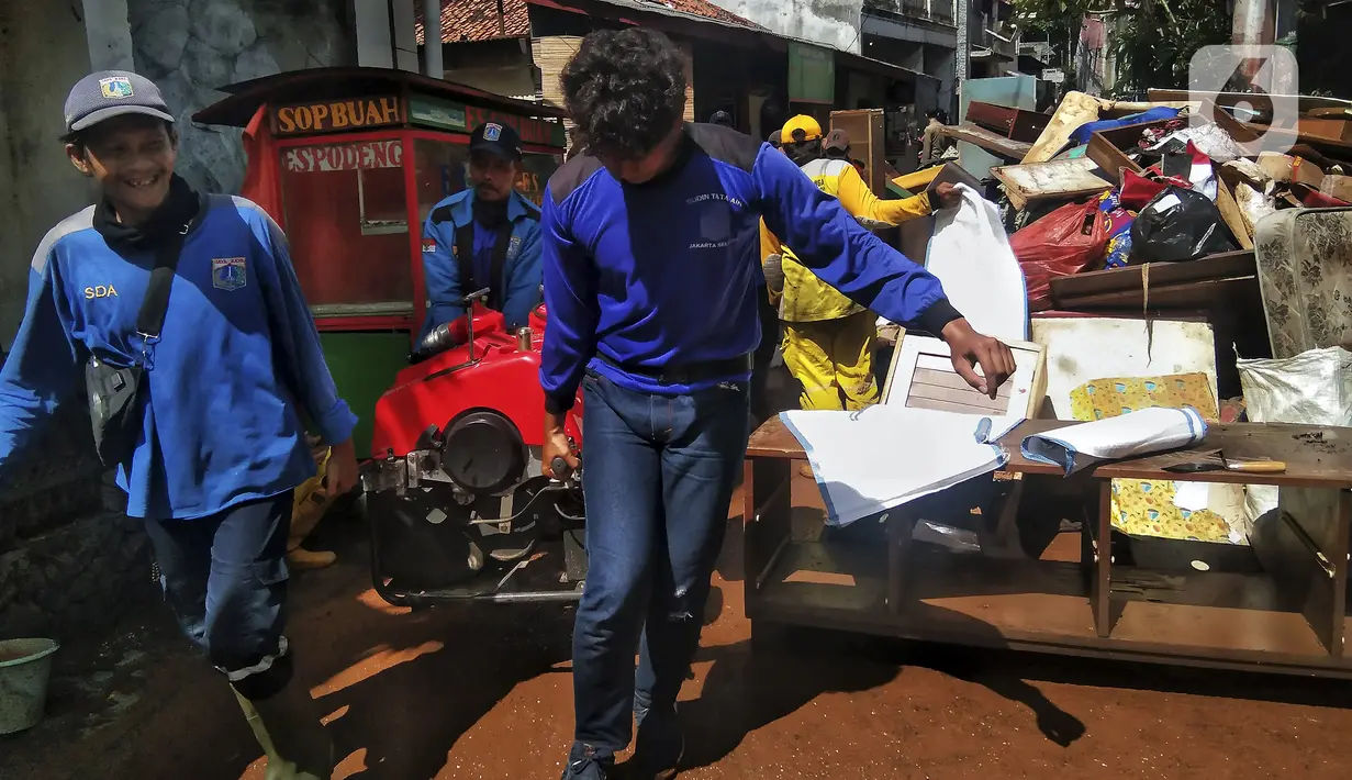 Petugas bekerja saat membersihkan sampah dan lumpur sisa banjir di Kebalen, Jakarta, Minggu (21/2/2021). Banjir yang terjadi kemarin karena curah hujan yang tinggi meninggalkan sampah di rumah warga. (Liputan6.com/Johan Tallo)