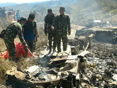 Tentara memeriksa puing dari pesawat Hercules TNI AU yang jatuh di kawasan Wamena, Papua, Minggu (18/12). Pesawat jenis C-130 HS A-1334 itu diduga jatuh menabrak Gunung Tugima sesaat akan mendarat di Bandara Wamena. (HANDOUT/SEARCH AND RESCUE TEAM/AFP)