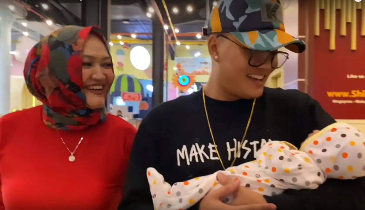 Rizky Febian juga terlihat beberapa kali menggendong sang adik. Ya, anak dari Lina dari pernikahannya yang sekarang. (YouTube @Putri Delina)