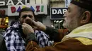 Seorang pria di Lebanon ditusuk pipinya dengan jarum panjang saat memperingati kelahiran Nabi Muhammad, Lebanon, Sabtu (3/1/2015). (AFP Photo/Mahmud Zayyat)