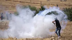Seorang pengunjuk rasa Palestina mengembalikan tabung gas air mata yang ditembakkan tentara Israel untuk membubarkan pengunjuk rasa saat membakar ban dan memblokir jalan yang melewati Desa Mughayer, Tepi Barat, utara Ramallah, 29 Juli 2022. Warga Palestina yang memprotes aktivitas permukiman Israel memblokir jalan utama dan bentrok dengan pemukim Israel, sementara tentara menembakkan gas air mata untuk membubarkan mereka. (AP Photo/Nasser Nasser)