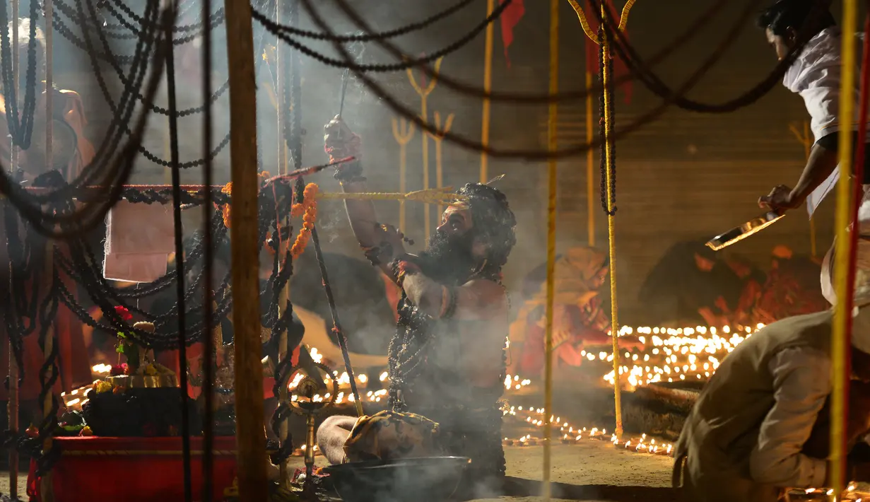 Seorang Sadhu India melakukan ritual keagamaan di luar kampnya saat acara tradisional Magh Mela di Sangam, India (2/1). Selama kurang lebih satu bulan, ribuan peziarah dan para Sadhu (orang suci umat Hindu) melakukan ritual. (AFP Photo/Sanjay Kanojia)