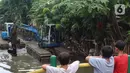 Anak-anak mengamati alat berat yang dioperasikan untuk pengerukan Kali Mampang, Pondok Jaya, Sabtu (19/2/2022). Pengadilan Tata Usaha Negara (PTUN) Jakarta mengabulkan gugatan warga pada 19-21 Februari 2021 terkait program pencegahan banjir yang dilakukan Pemprov DKI (Liputan6.com/Herman Zakharia)