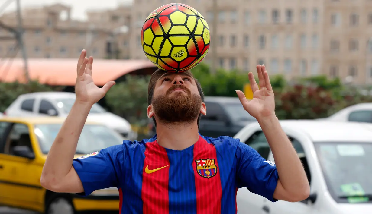 Pemuda asal Iran, Reza Parastesh menunjukkan kemampuannya mengolah bola di sebuah jalan di Teheran, Senin (8/5). Karena kemiripannya dengan Lionel Messi, Parastesh mendapat banyak tawaran wawancara dengan televisi setempat. (ATTA KENARE/AFP)
