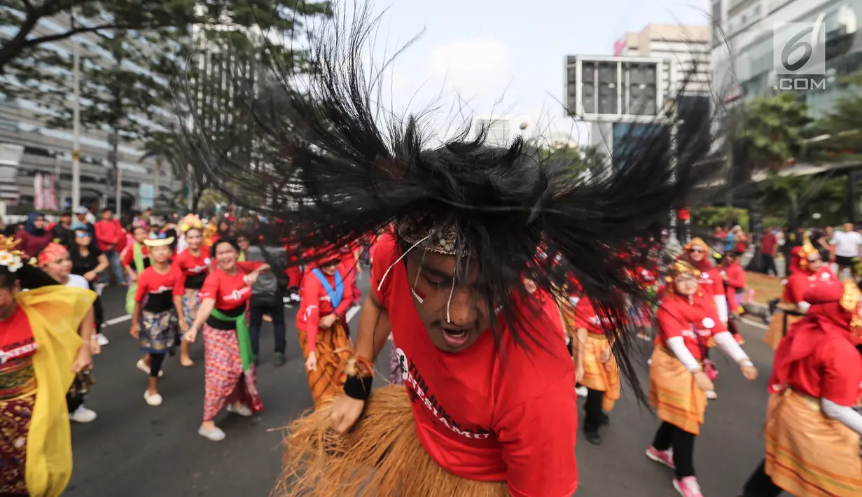 Seorang penari diikuti ribuan peserta membawakan Tari Yamko dari Papua saat CFD di Senayan, Jakarta, Minggu (12/8). Kegiatan ini digelar menyambut HUT Ke-73 RI dan Asian Games 2018. (Liputan6.com/Fery Pradolo)