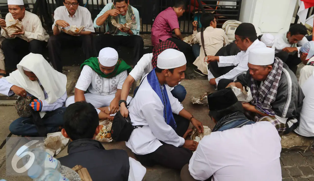 Massa aksi damai berkumpul makan di pinggir Jalan Medan Merdeka Timur, Jakarta, Jumat (4/11). Massa melakukan aksi di depan Istana Negara menuntut penegakan hukum kasus dugaan penistaan agama. (Liputan6.com/Faizal Fanani)