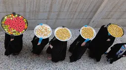 Sejumlah perempuan membawa kue untuk perayaan Idul Fitri yang akan datang di Basra, Irak, Jumat (22/5/2020). Idul Fitri menandai berakhirnya bulan suci Ramadan. (AP Photo/Nabil al-Jurani)