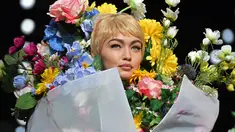 Top model Gigi Hadid mengenakan rancangan rumah mode Moschino saat Milan Fashion Week di Italia, Kamis (21/9). Dalam catwalknya Gigi Hadid mengenakan atribut penuh bunga di tubuhnya. (AFP Photo/Marco Bertorello)