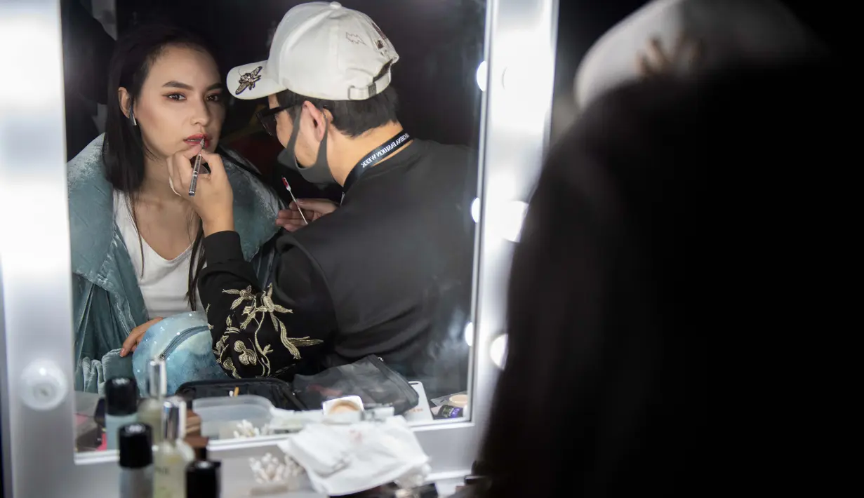 Model saat dirias di belakang panggung sebelum tampil membawakan koleksi Rabbit-Warm karya Zhuang Ganran selama China Fashion Week di Beijing (30/10). (AFP Photo/Nicolas Asfouri)