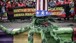 Gerakan Buruh untuk Rakyat (Gebrak) berunjuk rasa di depan Kedubes Amerika Serikat, Jakarta, Selasa (12/2). Massa pendemo membawa serta boneka gurita raksasa warna hijau yang dikenakan topi bermotif bendera Amerika Serikat. (Liputan6.com/Faizal Fanani)