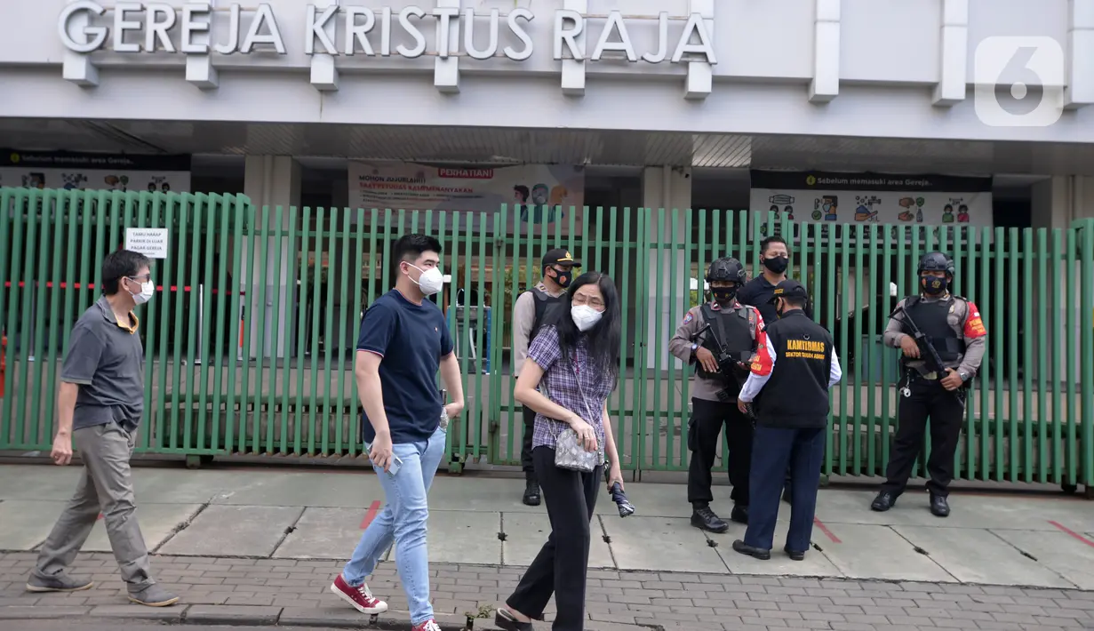 Jemaat berjalan saat polisi bersenjata berjaga di depan halaman Gereja Kristus Raja, Jakarta Jumat (2/4/2021). Penjagaan ini untuk pengamanan umat kristiani yang sedang melakukan ibadah Jumat Agung pada perayaan Paskah. (merdeka.com/Imam Buhori)