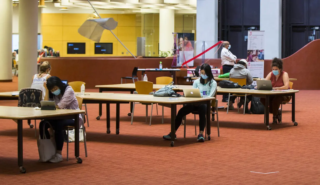 Orang-orang yang memakai masker menjaga jarak saat belajar di sebuah perpustakaan di Toronto, Kanada (24/8/2020). Tahap ketiga rencana pembukaan kembali Perpustakaan Umum Toronto dimulai pada Senin (24/8). (Xinhua/Zou Zheng)