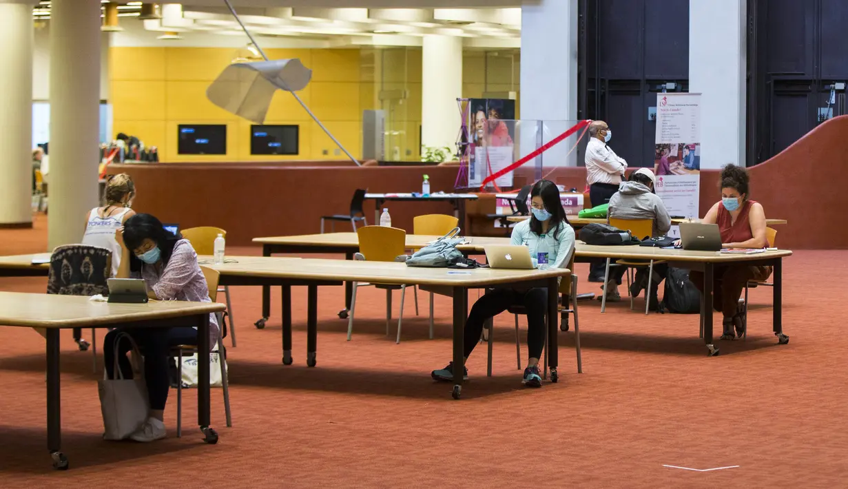 Orang-orang yang memakai masker menjaga jarak saat belajar di sebuah perpustakaan di Toronto, Kanada (24/8/2020). Tahap ketiga rencana pembukaan kembali Perpustakaan Umum Toronto dimulai pada Senin (24/8). (Xinhua/Zou Zheng)