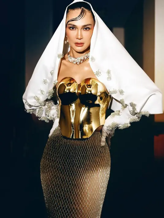 Di tangan stylist Allysha, Luna Maya tampil glamor di premier film Suzanna Malam Jumat Kliwon. Ia dibalut outer putih dengan aksen tutup kepala hingga menutup area tangannya yang memiliki detail payet bak bunga dan maxi skirt dari Etiquette White. Gaya Luna semakin glamor dengan mengenakan korset logam warna keemasan dari Morphacio. [@lunamaya]