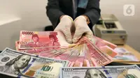 Karyawan menunjukkan uang rupiah dan dolar AS di Jakarta, Rabu (30/12/2020). Nilai tukar rupiah di pasar spot ditutup menguat 80 poin atau 0,57 persen ke level Rp 14.050 per dolar AS. (Liputan6.com/Johan Tallo)