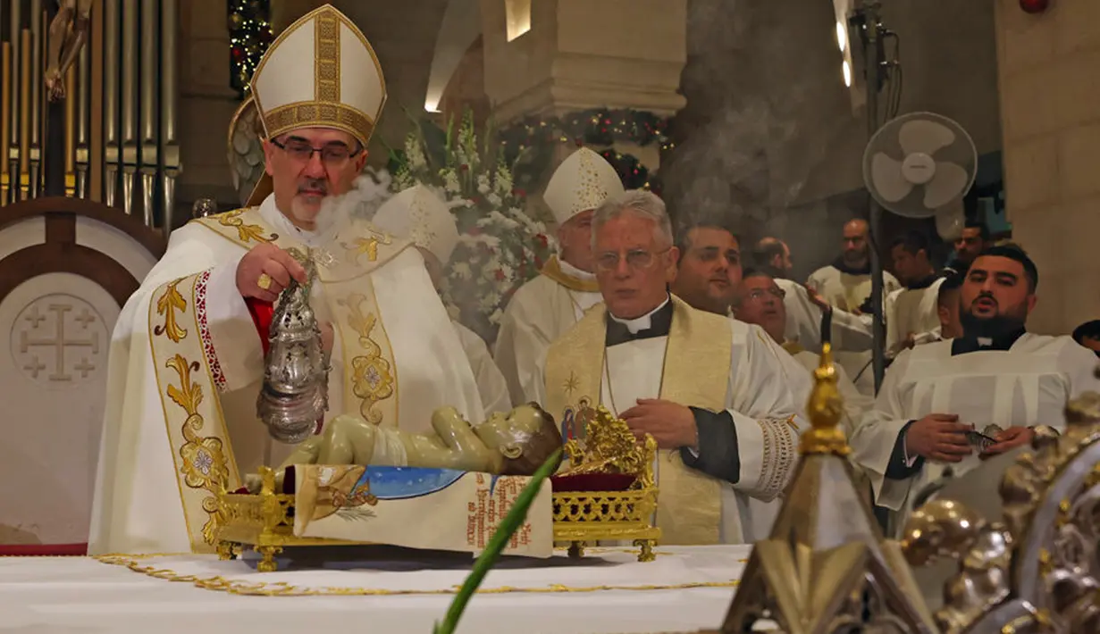 <p>Patriark Latin Yerusalem, Pierbattista Pizzaballa memimpin Misa Malam Natal di Kompleks Gereja Kelahiran Yesus, Bethlehem, Tepi Barat, Minggu (25/12/2022). Setelah dua tahun tutup karena COVID-19, jemaat kembali menghadiri ibadah tersebut kendati jumlahnya tidak sebanyak sebelum pandemi. (Ahmad Gharabli/Pool Photo via AP)</p>