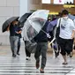 Pejalan kaki mencoba berlindung dari angin dan hujan saat mereka menyeberang jalan di depan Stasiun Osaka pada 15 Agustus 2023, saat Badai Tropis Lan menerjang pulau utama Honshu pada malam hari. (Dok:&nbsp;STR / JIJI Press / AFP)