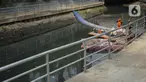 Petugas membersihkan sampah di sepanjang Kali Taman Anggrek, Jakarta, Rabu (8/7/2020). Banyaknya limbah menyebabkan Kali Taman Anggrek menjadi berwarna hitam dan berbau tidak sedap meskipun dibersihkan setiap hari. (Liputan6.com/Immanuel Antonius)