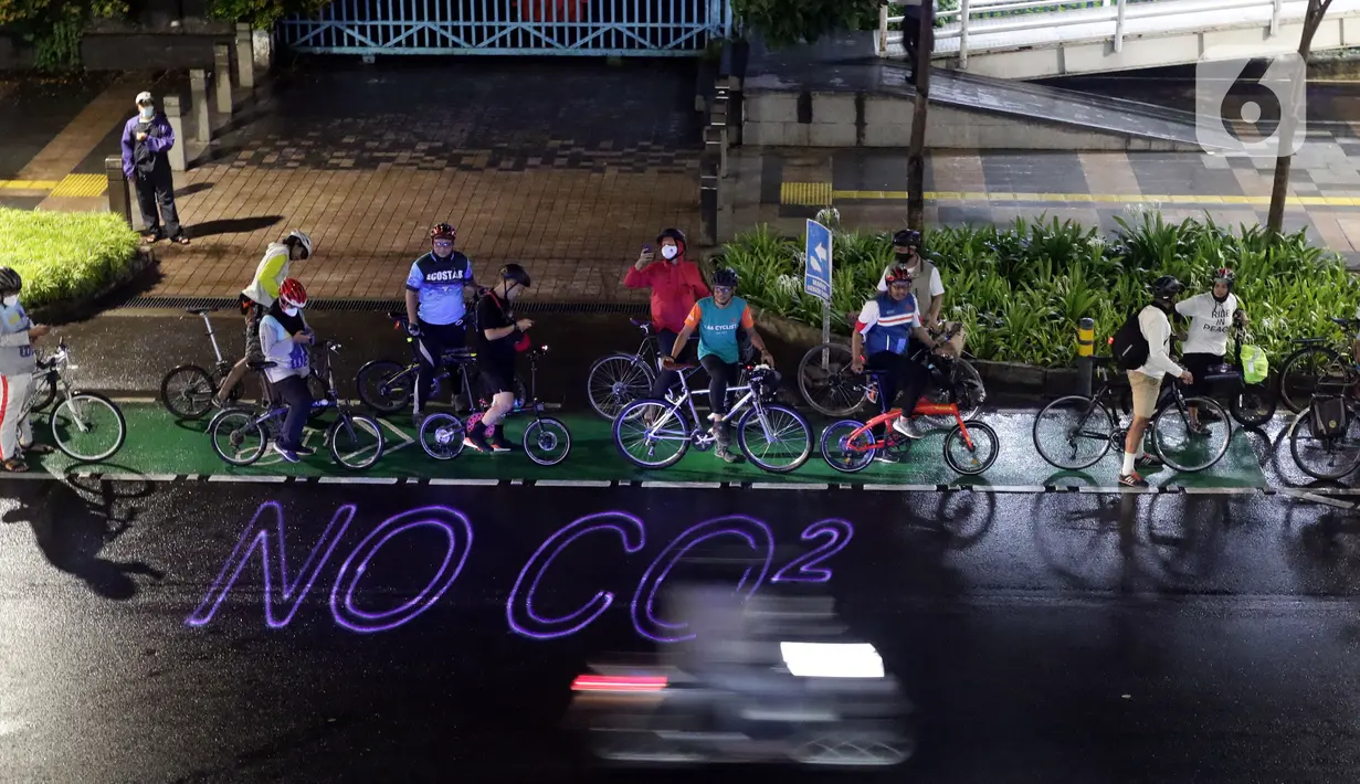 Pegiat bersepeda dan aktivis pecinta lingkungan saat aksi gowes Kelap Kelip Jakarta Night Ride #NOP26 di Kawasan Dukuh Atas, Jalan Jenderal Sudirman, Jakarta, Jumat (26/11/2021). Aksi bertujuan untuk mendorong penggunaan sepeda sebagai solusi transportasi nol emisi. (Liputan6.com/Helmi Fithriansyah)