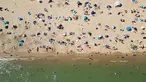 Foto udara menunjukkan orang-orang bermain dan bersantai di bawah sinar matahari di Pantai Bournemouth, Selatan Inggris pada Selasa 26 Mei 2026, saat kondisi gelombang panas menyebar ke sebagian wilayah tenggara Inggris dan London. (JUSTIN TALLIS/AFP)