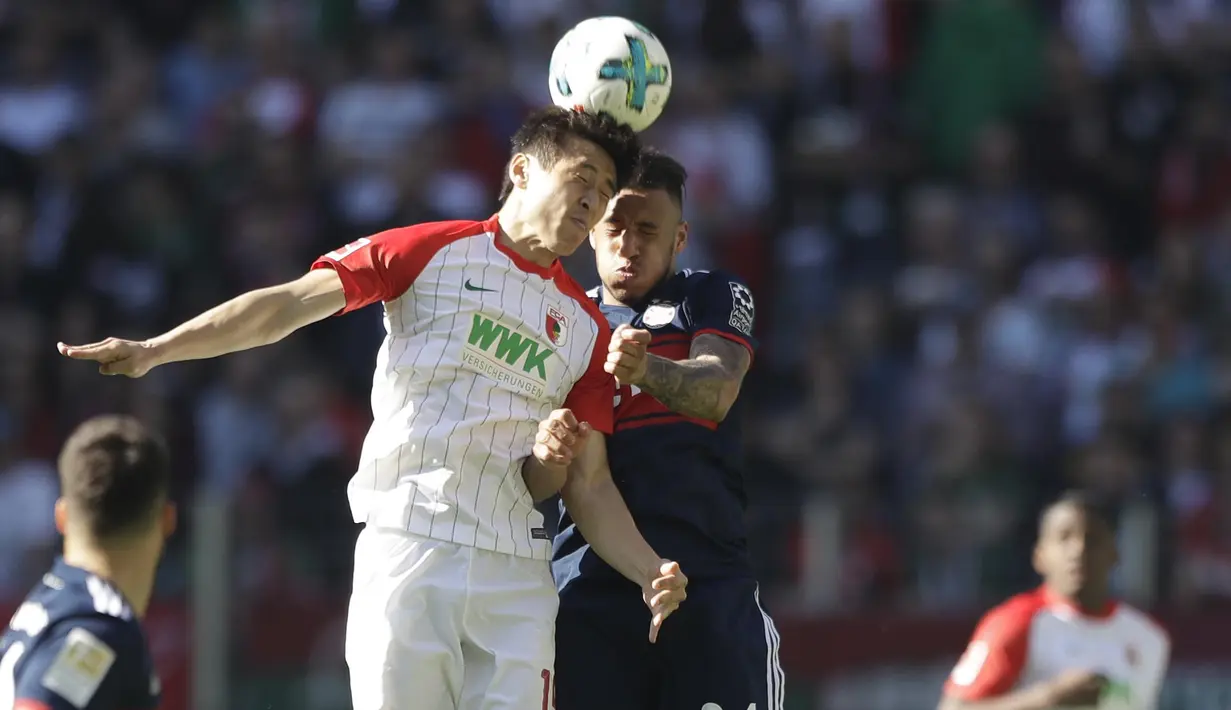 Gelandang Bayern Munchen, Corentin Tolisso, duel udara dengan gelandang FC Augsburg, Koo Ja-cheo, pada laga Bundesliga di WWK Arena, Augsburg, Sabtu (7/4/2018). Bayern Munchen menang 4-1 atas FC Augsburg. (AP/Matthias Schrader)