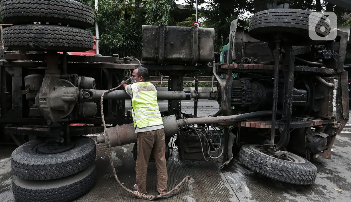 Petugas melakukan evakuasi Kontainer yang terguling di Jalan S Parman, Jakarta Barat, Senin (4/5/2020). Tidak ada korban jiwa dalam kecelakaan tersebut, namun kecelakaan tersebut membuat lalin dijalan itu terimbas kemacetan yang cukup panjang. (Liputan6.com/Johan Tallo)