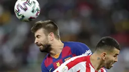 Bek Barcelona, Gerard Pique menyundul bola melewati pemain Atletico Madrid Angel Correa pada laga semifinal Piala Super Spanyol di King Abdullah Sports City, Jeddah, Kamis (9/1/2020). Barcelona harus menjalani pertandingan yang dramatis saat kalah 2-3 dari Atletico Madrid. (AP/Hassan Ammar)