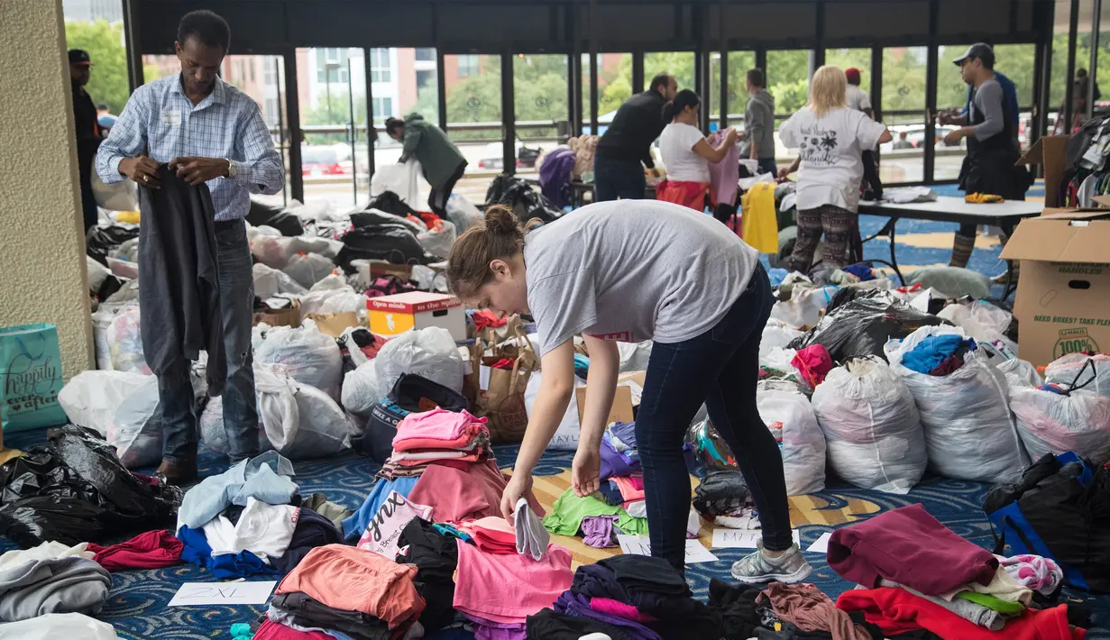 Seorang relawan memilah baju hasil donasi sebelum dibagikan kepada korban Harvey di Houston, Selasa (29/8). Puluhan badan amal terpercaya lainnya turut membantu aksi penggalangan dana untuk korban Harvey. (Marie D. De Jesus/Houston Chronicle via AP)