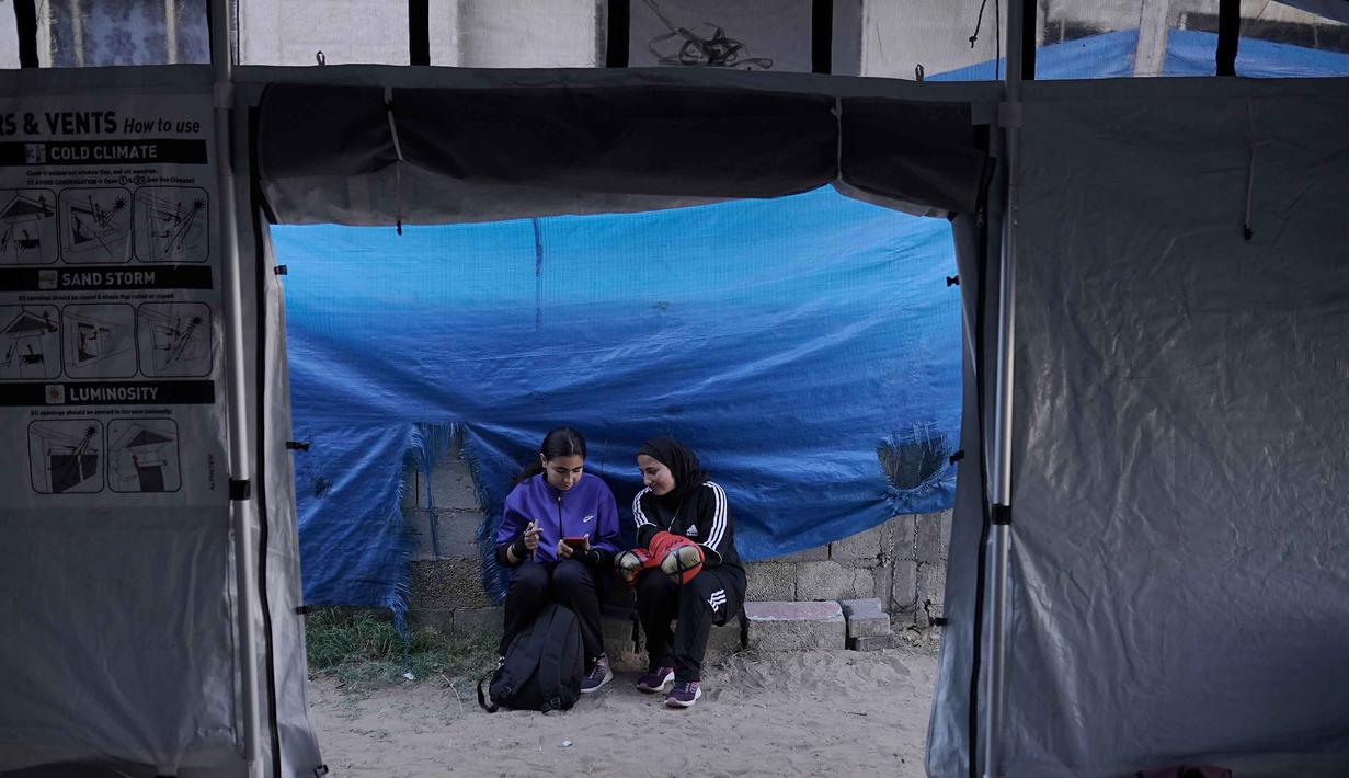 Di antara deretan tenda darurat pengungsi Palestina di kawasan Khan Younis, Jalur Gaza Selatan, sejumlah gadis belia memukul karung berisi pasir yang digantung seadanya pada tiang-tiang penyangga. Tampak dalam foto, gadis-gadis Palestina beristirahat setelah berlatih di klub tinju wanita yang didirikan di dalam tenda di Kota Gaza, Selasa 5 Mei 2026. (AP Photo/Jehad Alshrafi)