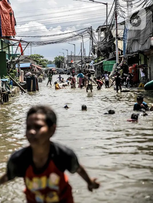Sejumlah anak bermain air banjir rob di kawasan Muara Angke, Jakarta, Selasa (9/11/2021). Badan Penanggulangan Bencana Daerah (BPBD) DKI Jakarta memperkirakan puncak musim hujan dan potensi rob di Ibu Kota terjadi pada Januari hingga Februari 2022. (Liputan6.com/Faizal Fanani)