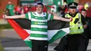 Seorang suporter membawa bendera Palestina saat akan menyaksikan pertandingan melawan Hapoel Beer Sheva di babak kualifikasi play off Liga Champions di Celtic park, (19/8). Fans Celtic telah merencanakan aksi ini sejak jauh hari. (REUTERS/Russell Cheyne)