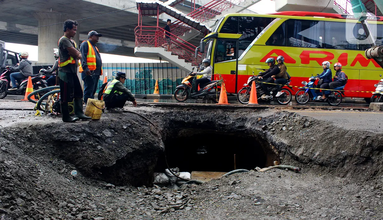 Pekerja memperbaiki jalan ambles di Jalan Daan Mogot, Tangerang, Banten, Senin (13/1/2020). Amblesnya jalan penghubung ke Jakarta ini diduga karena adanya kebocoran pipa PDAM Tirta Kerta Raharja milik Pemkab Tangerang yang mengikis struktur tanah. (merdeka.com/Magang/Muhammad Fayyadh)