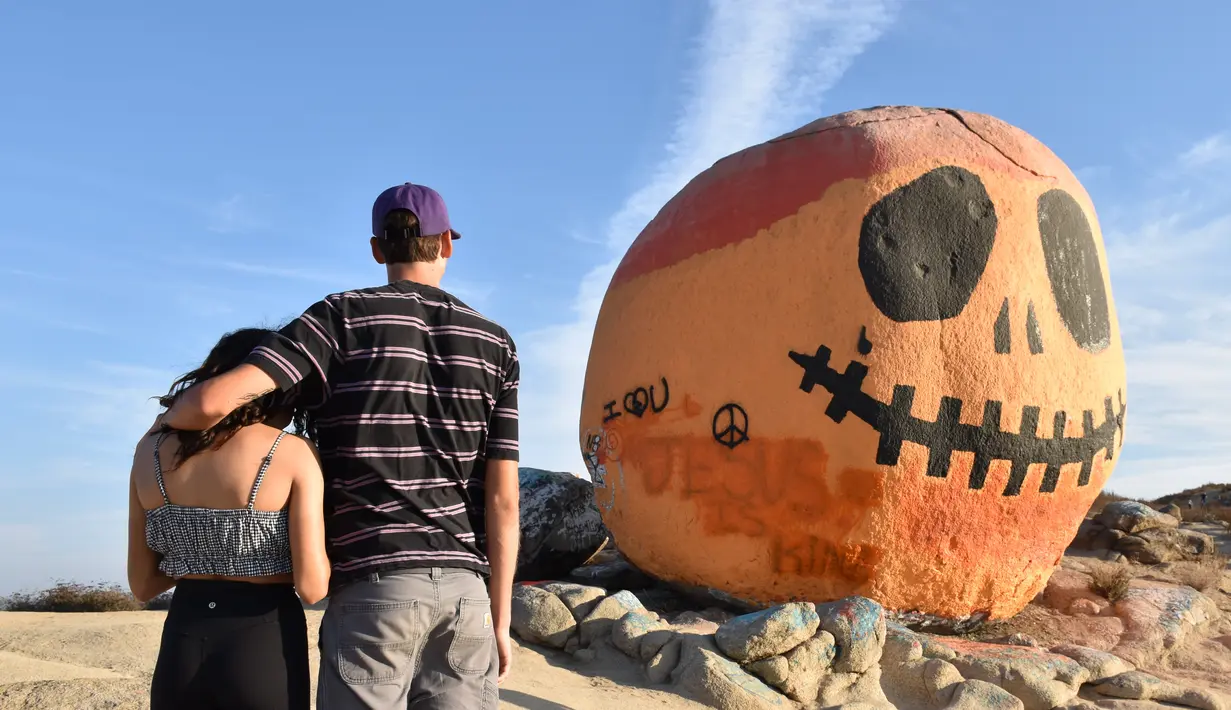 Orang-orang mengunjungi Pumpkin Rock (Batu Labu) di puncak sebuah bukit di Norco,  California, AS (18/10/2020). Menjelang perayaan Halloween, Pumpkin Rock, sebongkah batu raksasa yang dilukisi seperti Jack-O'-Lantern besar, menjadi objek wisata yang populer bagi pengunjung. (Xinhua/Gao Shan)